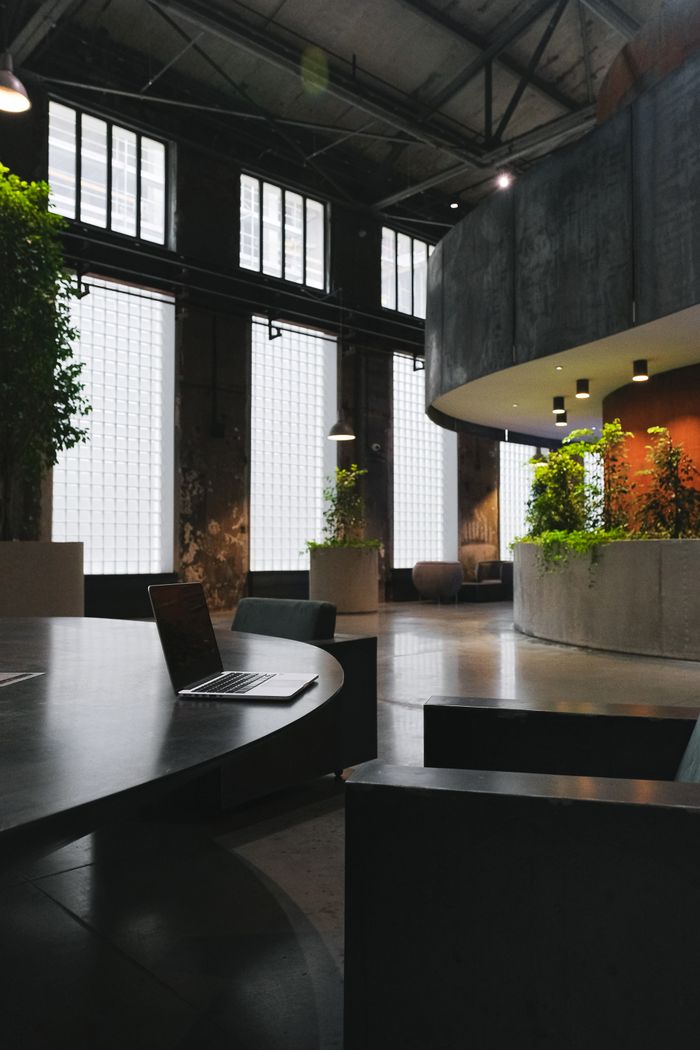 A spacious, contemporary office featuring a laptop on a table and indoor plants adding greenery.
