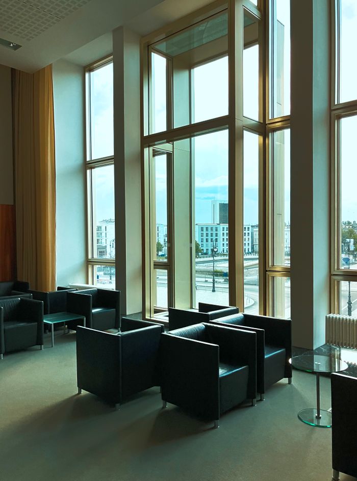 Services Spacious contemporary lobby with panoramic windows and stylish black chairs in Berlin.